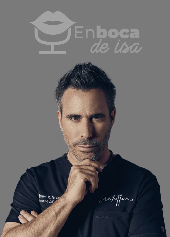 Un hombre de pelo y barba gris se encuentra de pie sobre un fondo gris. Lleva una camisa negra y se sostiene la barbilla con una mano. El logo "En boca de isa" se muestra sobre él, capturando la esencia de Isabel Restrepo, conocida por su trabajo en Mentoring Miami.