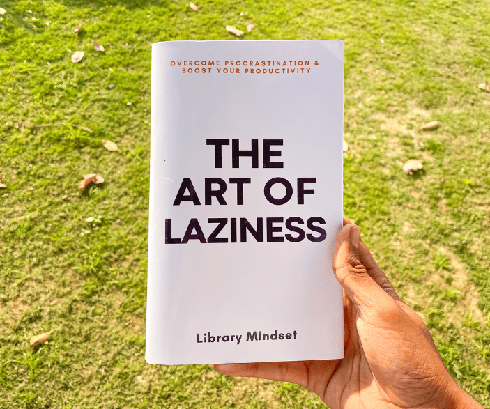 Una mano sosteniendo un libro titulado "El arte de la pereza: supere la procrastinación y aumente su productividad" de Library Mindset, con un fondo de césped, perfecto para su próximo evento de Speaker Miami.