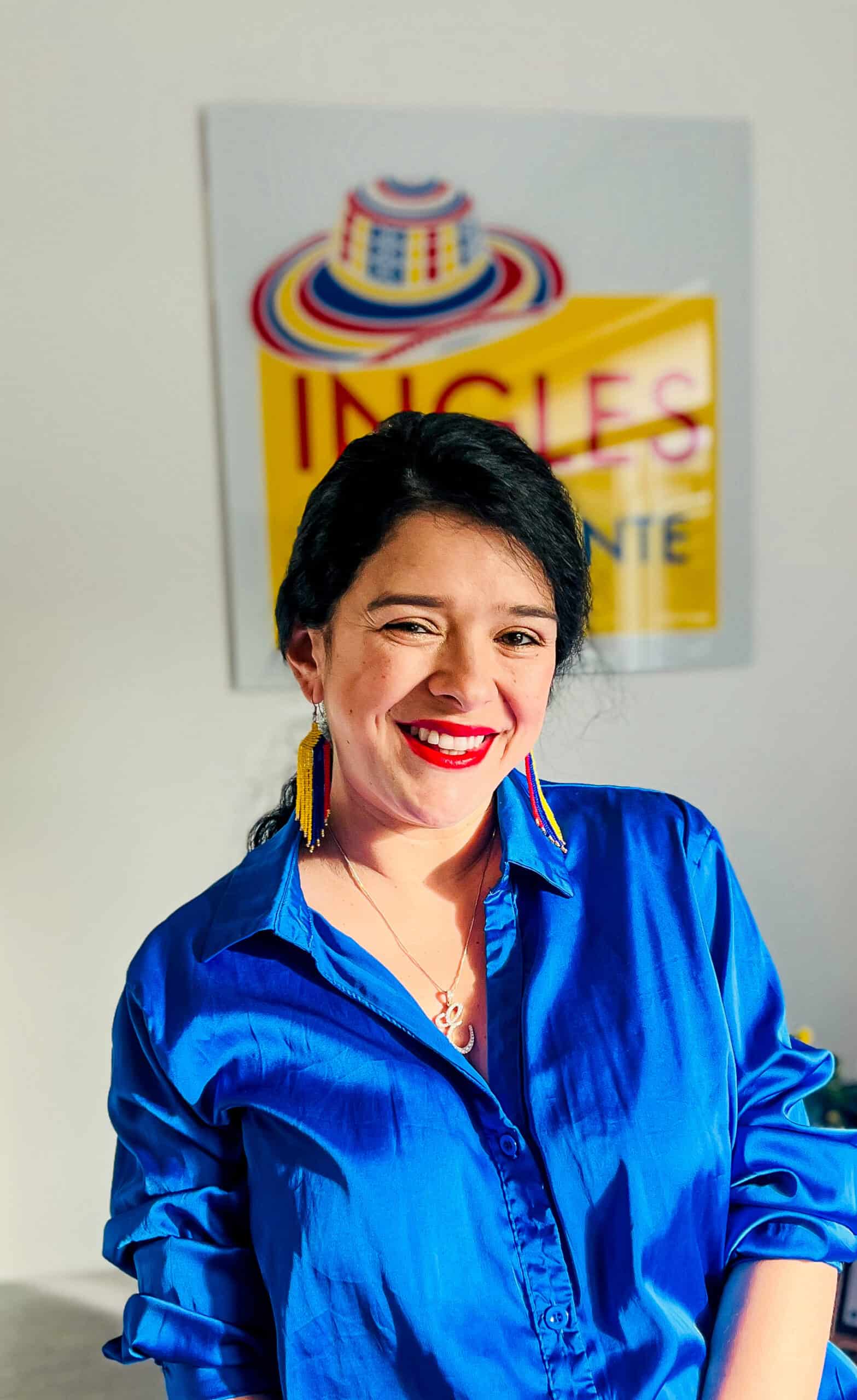 Una mujer con una camisa azul sonríe frente a un cartel con texto, encarnando el espíritu vibrante de Mentoring Miami.