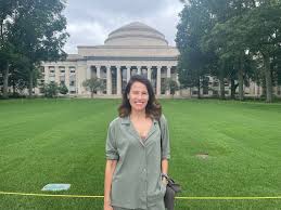 Rosa Fernández-Velilla aparece sonriendo sobre un césped verde con un edificio abovedado y con columnas al fondo en un día nublado.