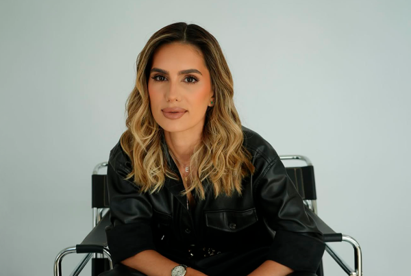 Eddy Vera sentada en una silla, con cabello ondulado y atuendo negro, mirando al frente con expresión segura y profesional